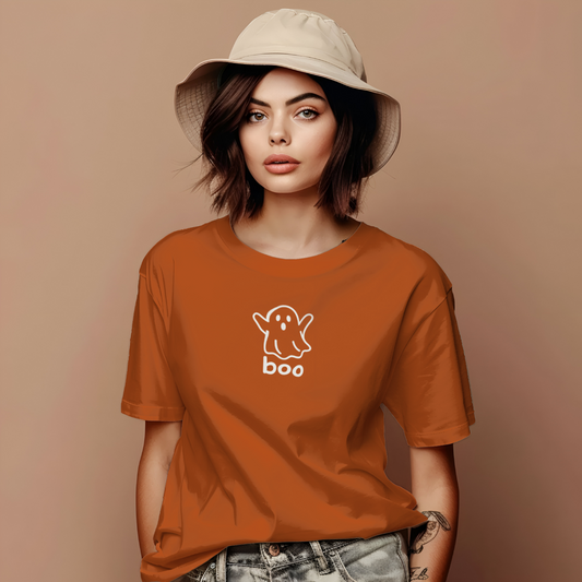 Person wearing an orange t-shirt with a ghost and 'boo' design on a beige background