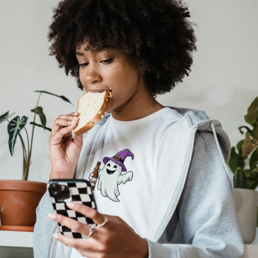 Person eating a sandwich and looking at a phone with a ghost design on a hoodie