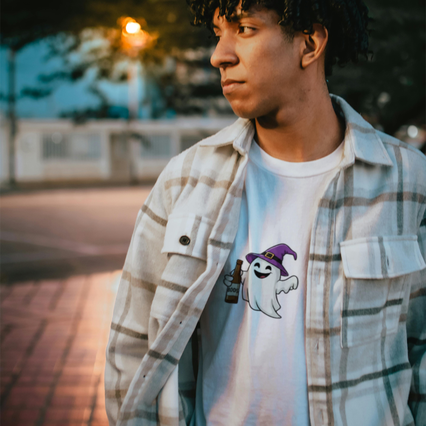 Person wearing a plaid shirt over a graphic t-shirt with a ghost design outdoors.