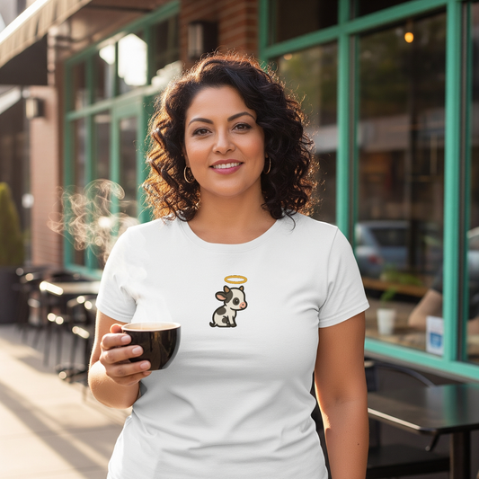 Woman holding a coffee cup outdoors, wearing a white t-shirt with a cow graphic and angel wings.