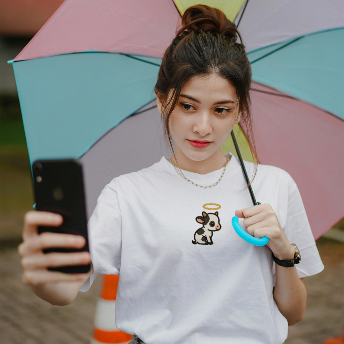 Person holding a colorful umbrella and taking a selfie with a phone.