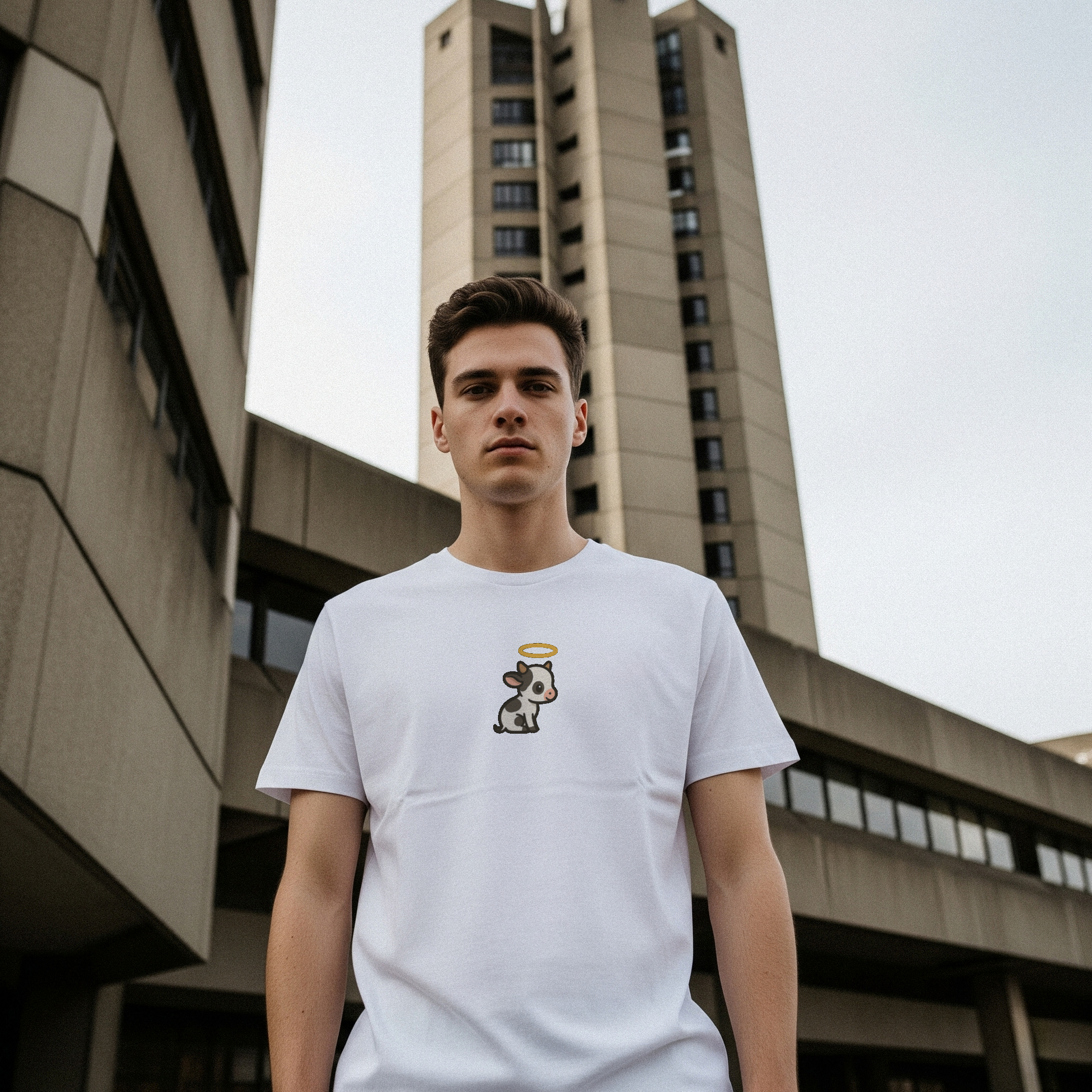 Person wearing a white t-shirt with a holy cow graphic in front of a building