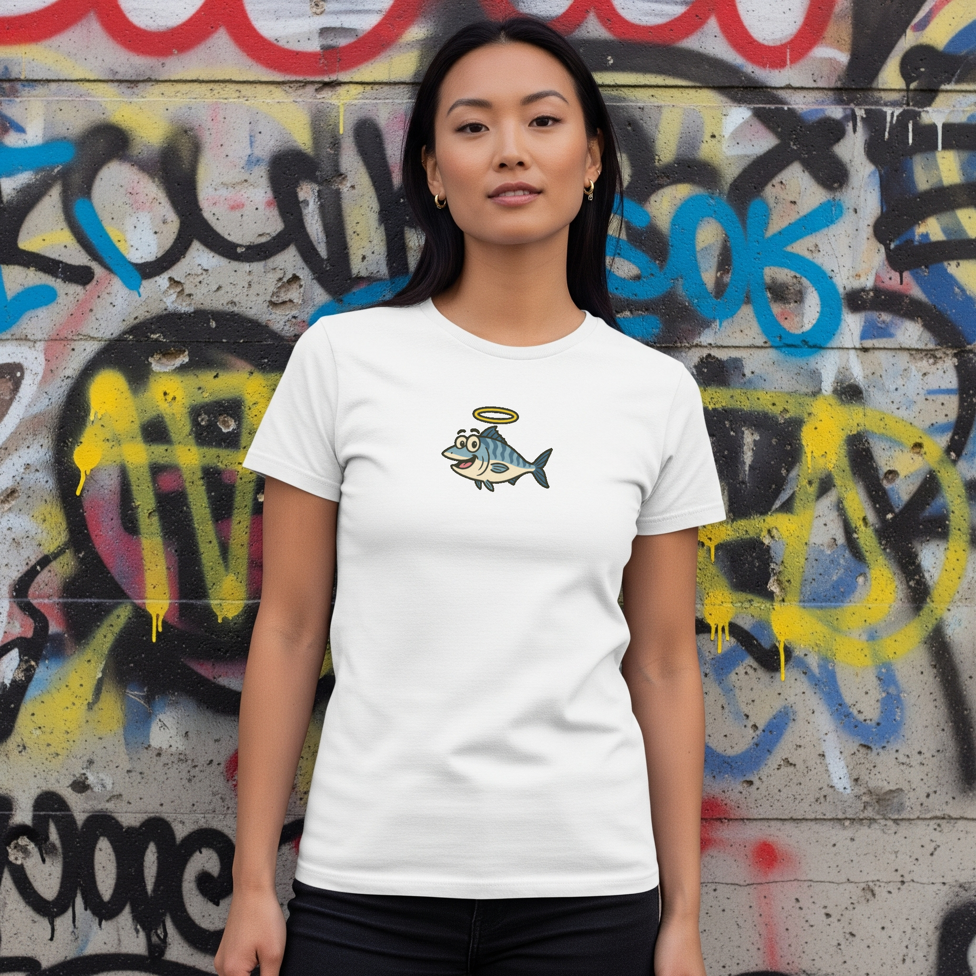 Person wearing a white t-shirt with a fish graphic in front of a graffiti-covered wall.
