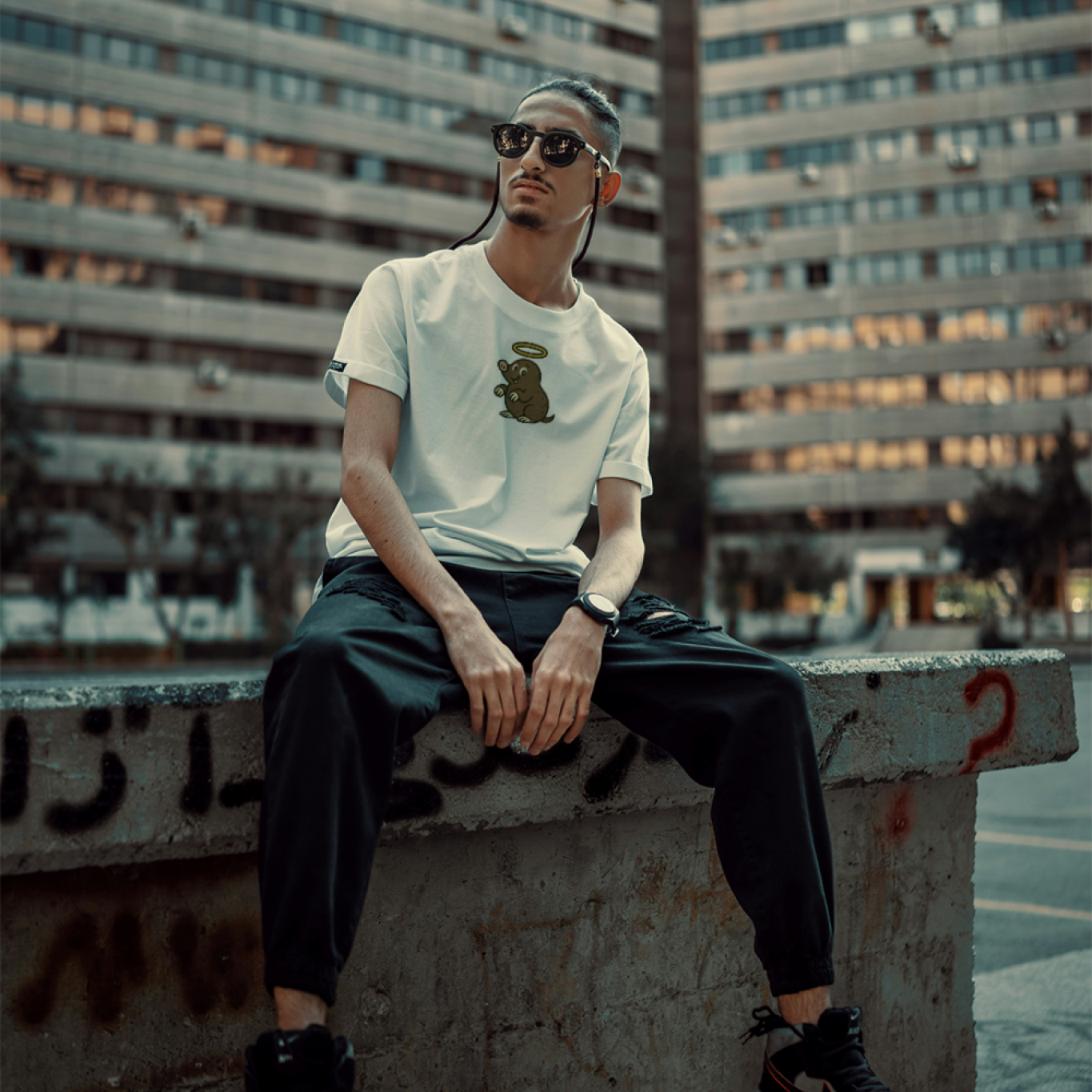 Person sitting on a concrete ledge in an urban setting with a building in the background