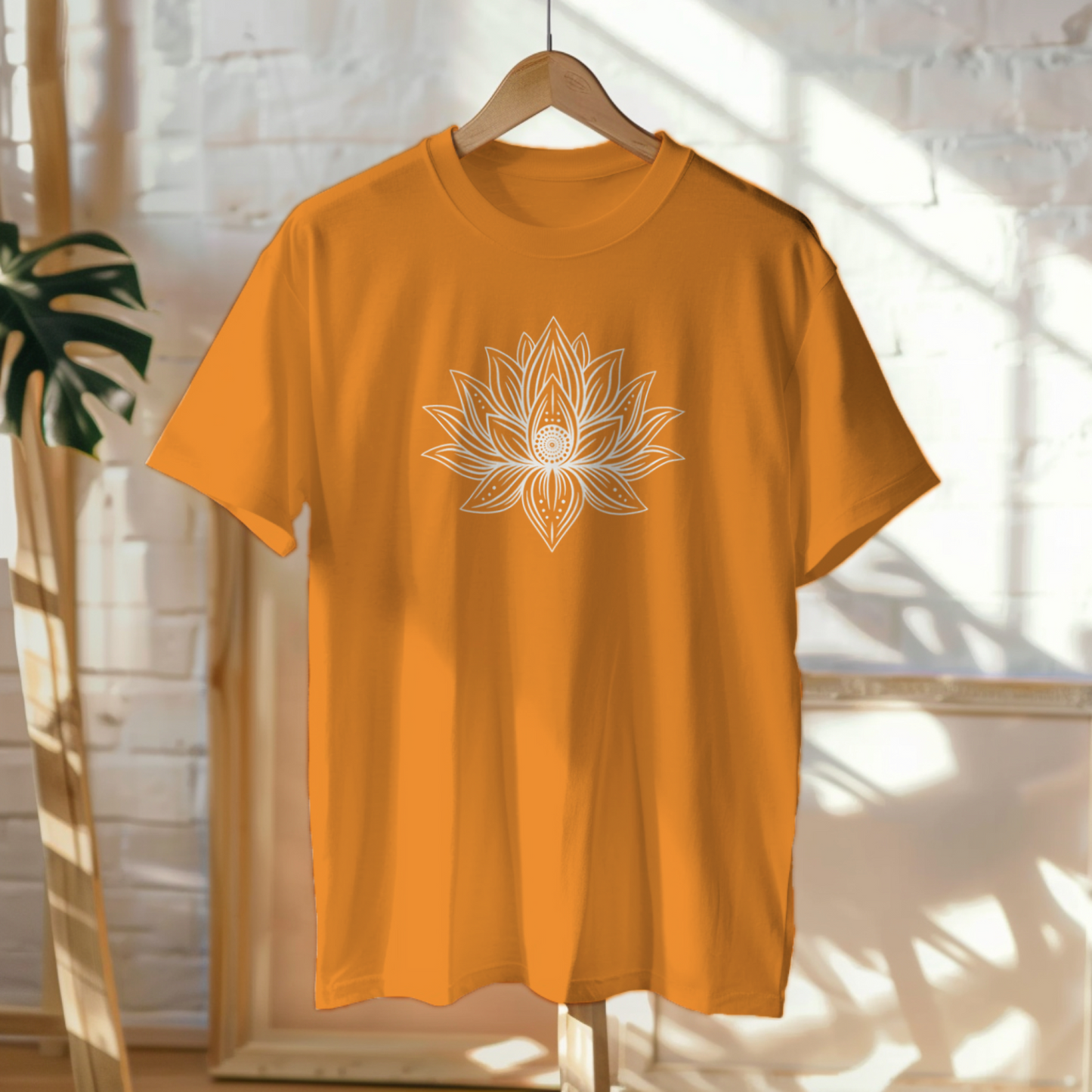 Orange t-shirt with a white lotus flower design on a hanger against a light background