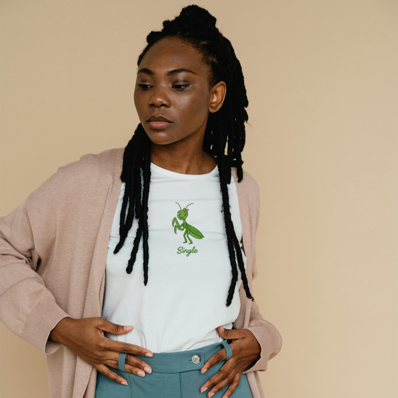Woman wearing a white t-shirt with a Single praying mantis and teal pants against a beige background