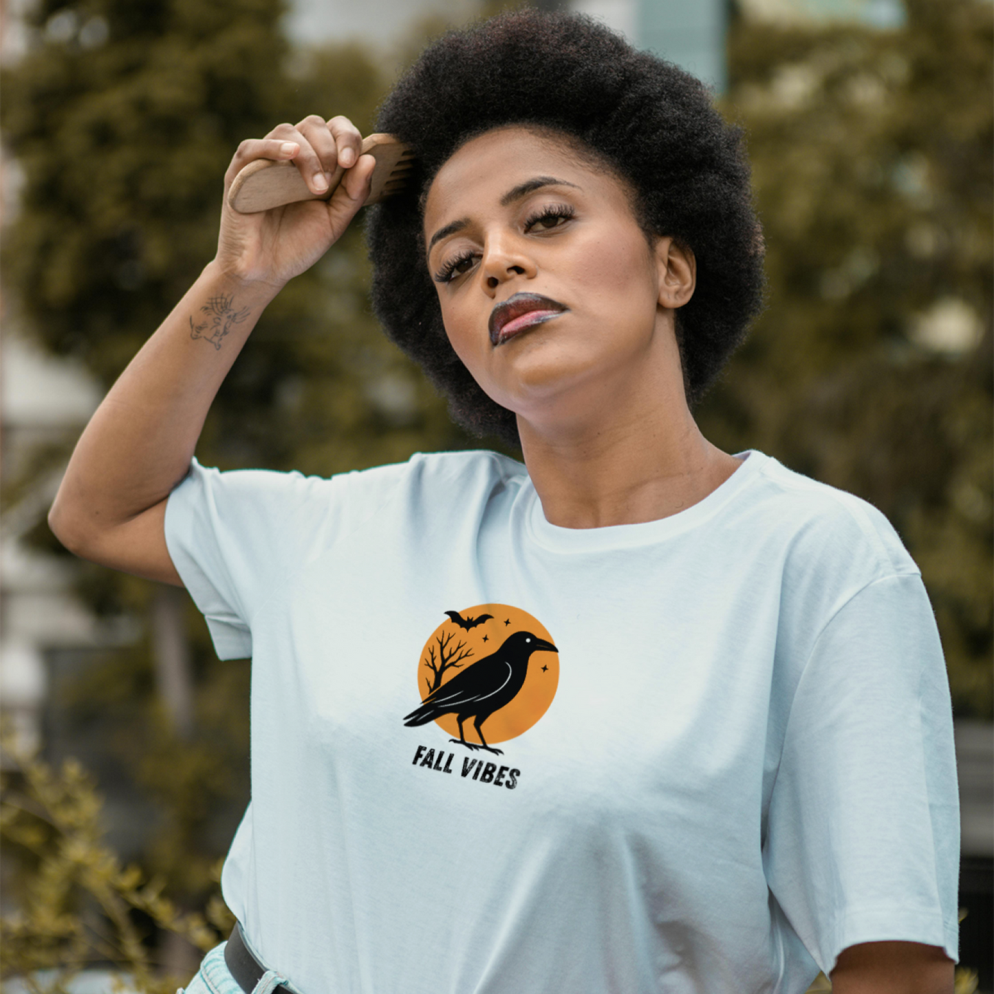 Woman wearing a light blue t-shirt with a 'Fall Vibes' graphic design outdoors.