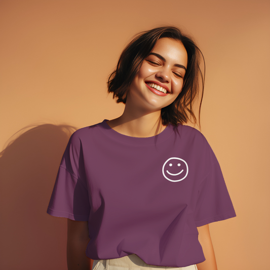Woman wearing a purple t-shirt with a smiley face design against a beige background