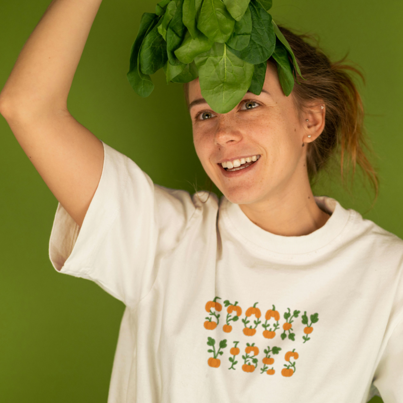 Person wearing a white t-shirt with a vegetable-themed design against a green background