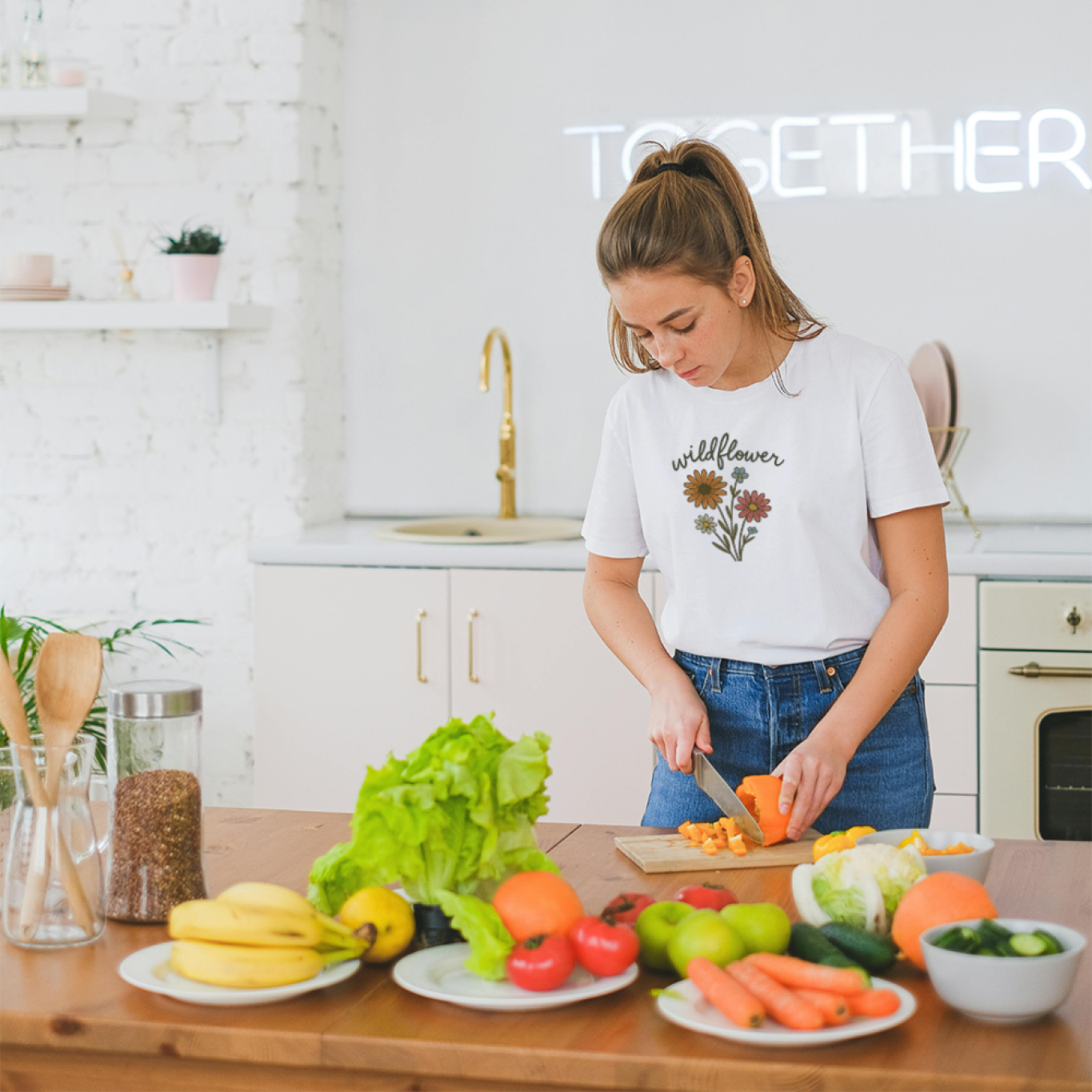 Woman preparing food in a kitchen while wearing a Wildflower shirt