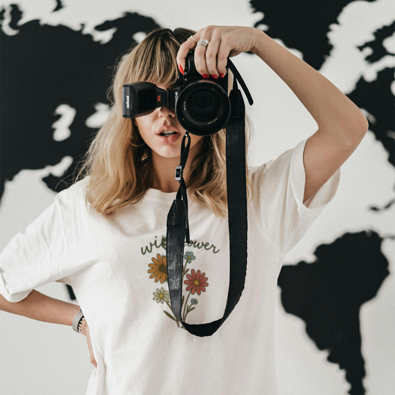 Woman holding a camera and wearing a Wildflower bohemian shirt