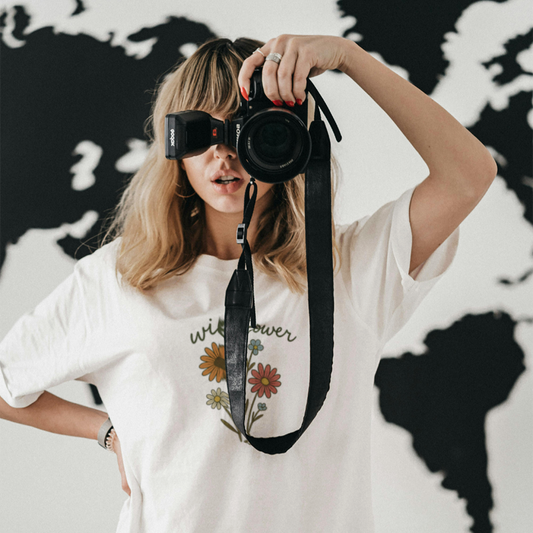Woman holding a camera and wearing a Wildflower bohemian shirt